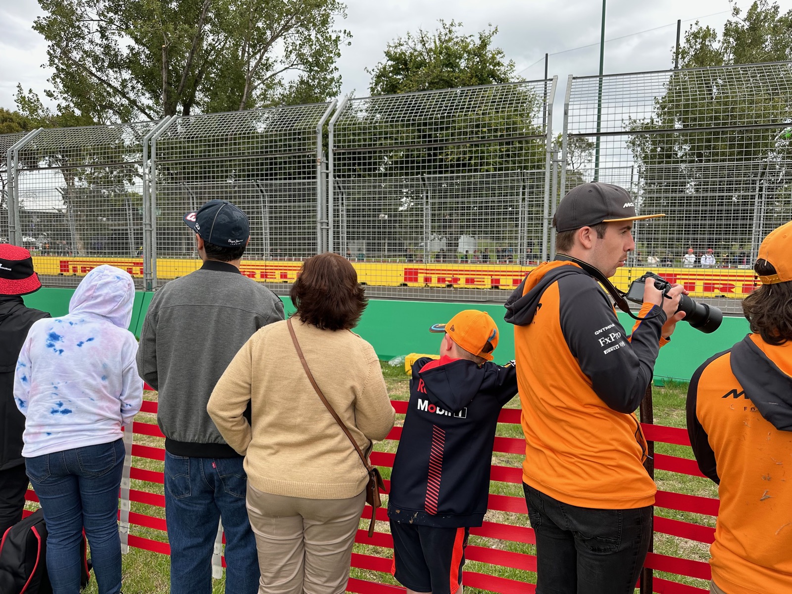 Fans eagerly watch the Grand Prix from behind barriers in Australia, capturing the thrilling race atmosphere.
