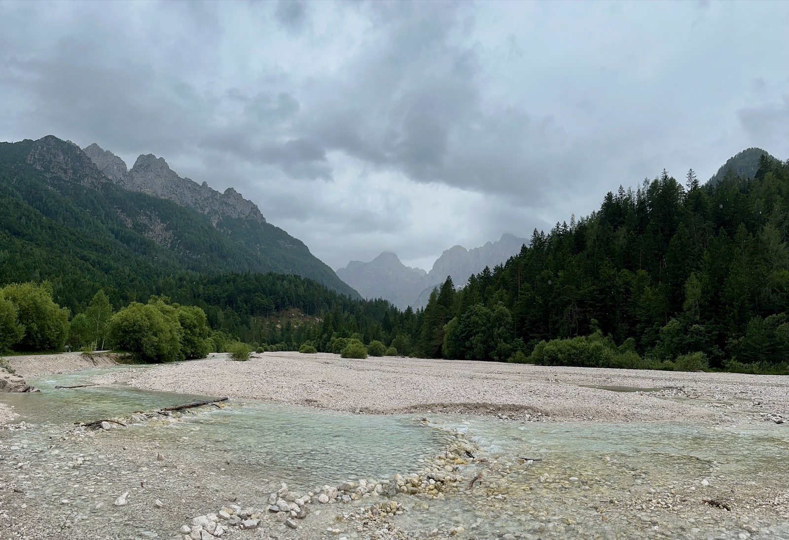 River with rocks and trees under cloudy sky.