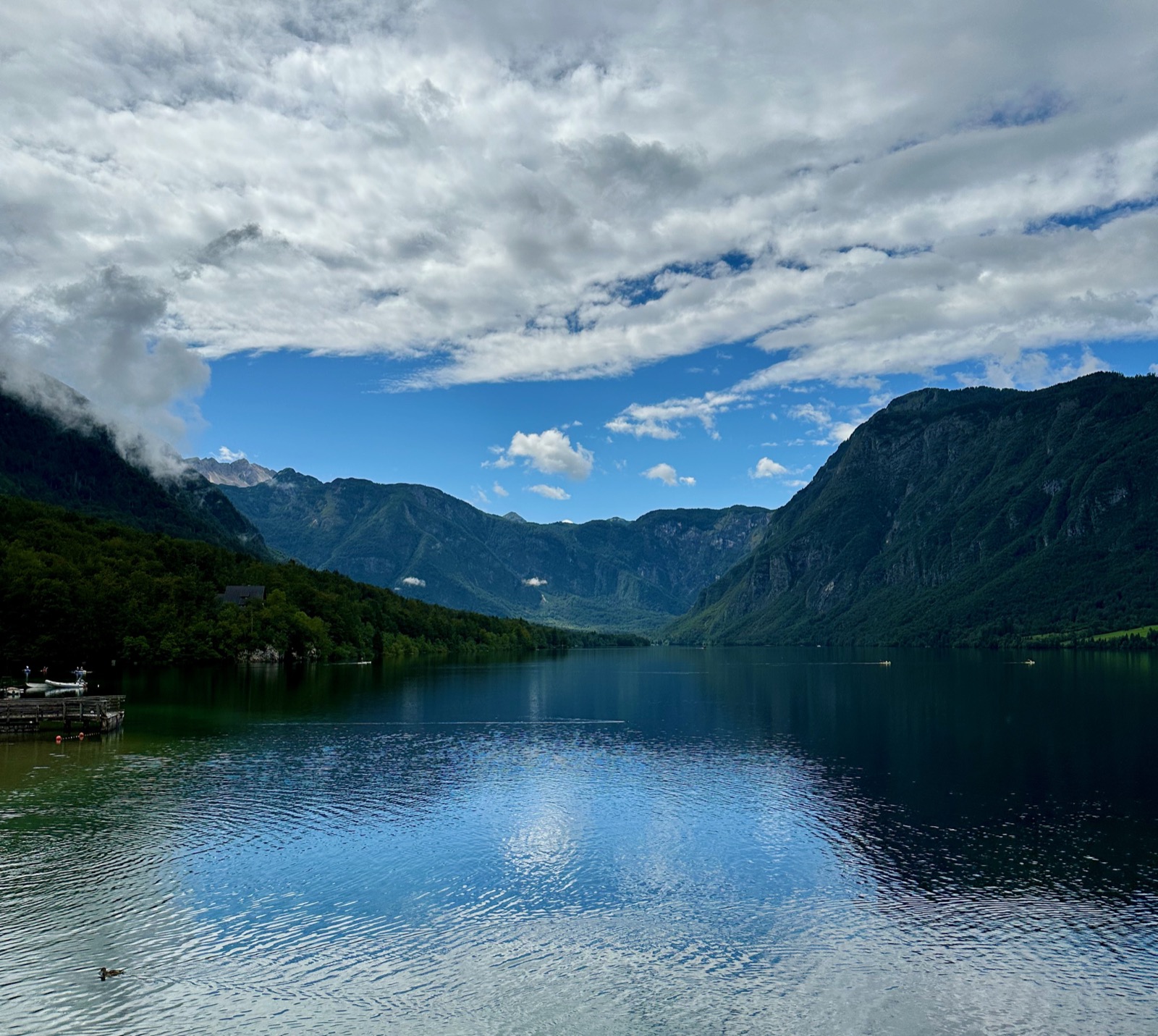 A lake with mountains and a partly cloudy sky.