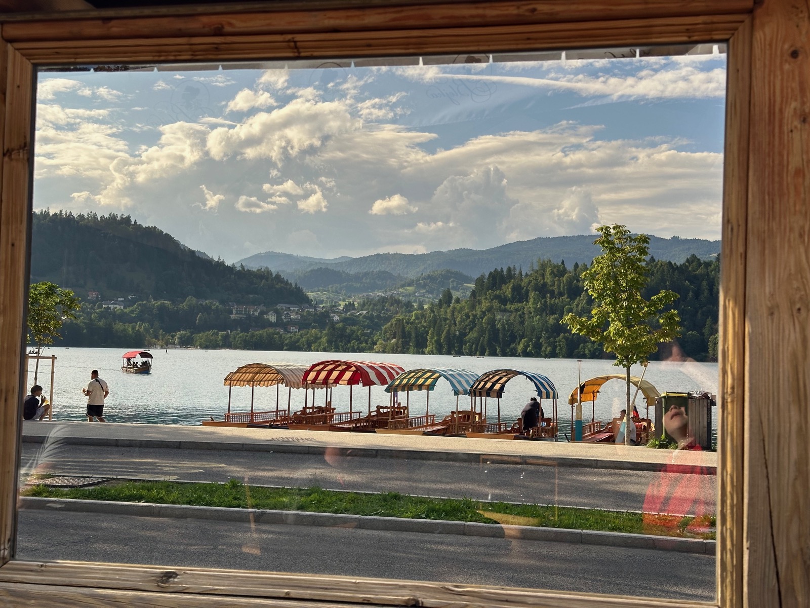 Wooden boats with striped canopies on a dock by a lake with mountains in the background.