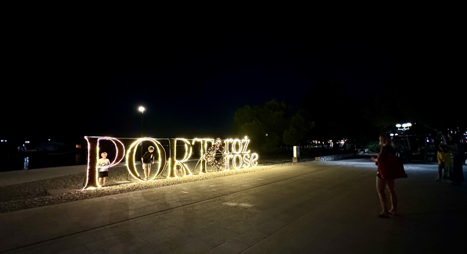 Portoroz's illuminated sign shines brightly against the night sky, inviting visitors to explore its coastal charm.