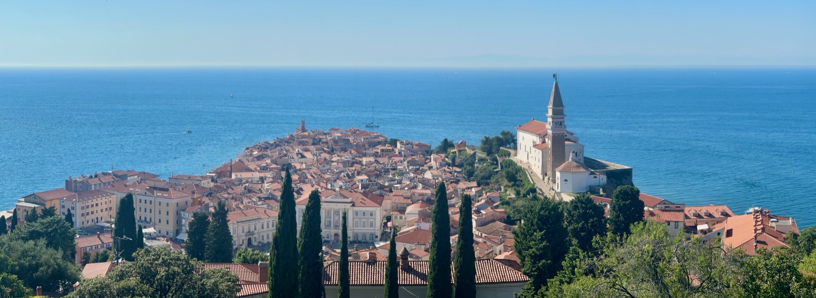 Portoroz's coastal charm shines with red-roofed buildings and a historic church overlooking the Adriatic Sea.