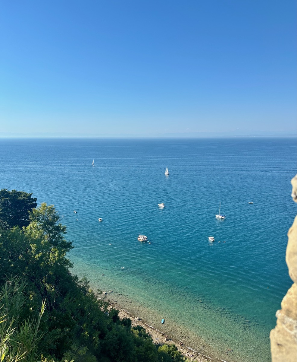 Portoroz, Slovenia, dazzles with azure waters and sailboats dotting the serene coastline under a clear blue sky.