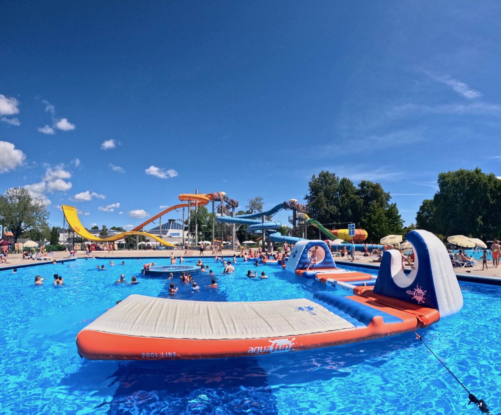 Dive into fun at Terme Catez, Slovenia's vibrant water park with slides and inflatables under a clear blue sky.